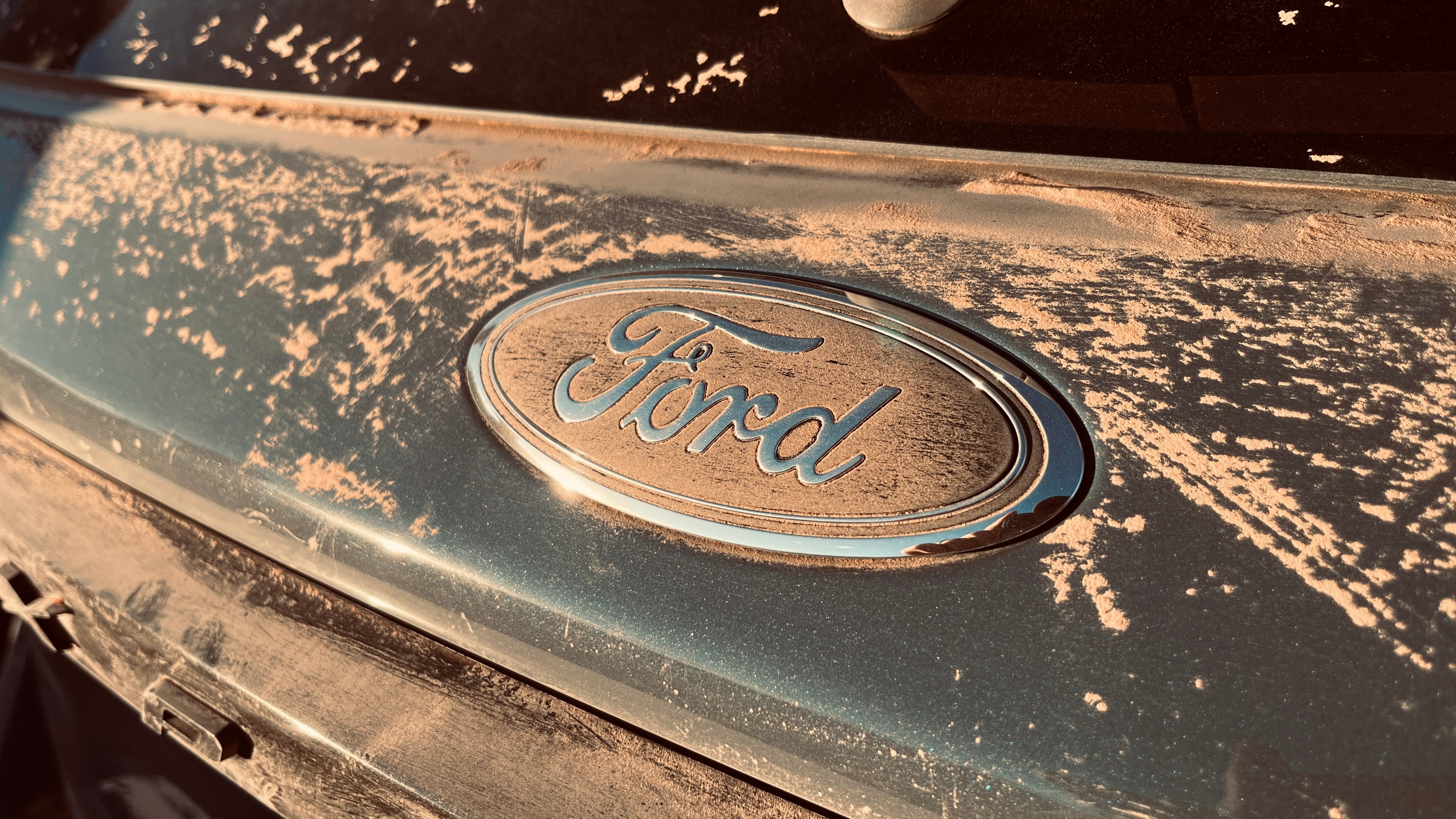 The "Ford" nameplate on an Exlorer covered in dirt.